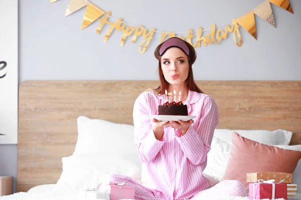 Mujer feliz con pastel de cumpleaños sentado en la cama en casa —  Fotos de Stock