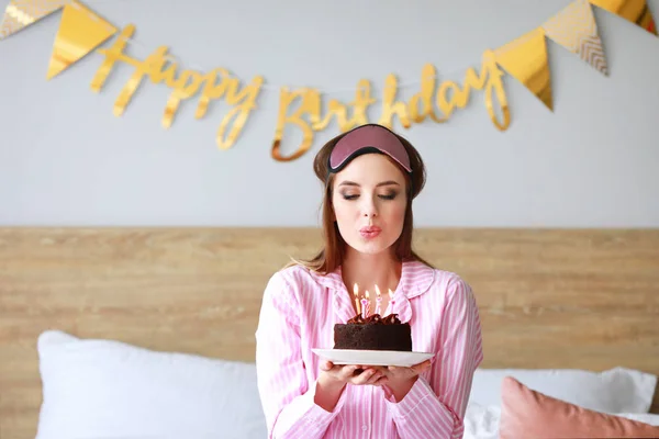 Mujer feliz soplando velas en el pastel de cumpleaños en casa — Foto de Stock