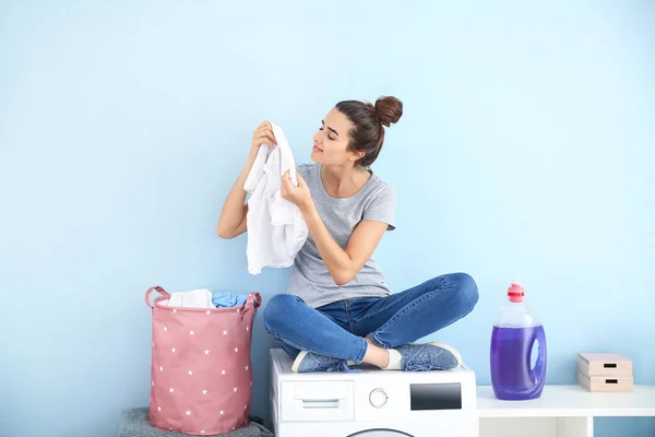 Mulher bonita com lavandaria limpa sentado na máquina de lavar roupa em casa — Fotografia de Stock