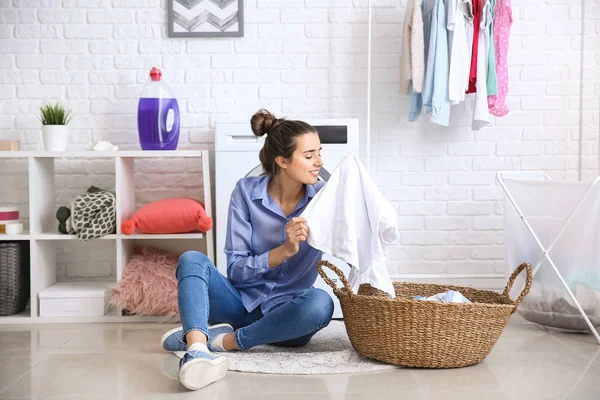 Beautiful young woman doing laundry at home — Stock Photo, Image