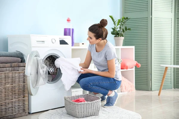 Beautiful young woman doing laundry at home — Stock Photo, Image