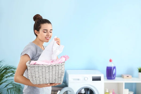 Beautiful young woman doing laundry at home — Stock Photo, Image