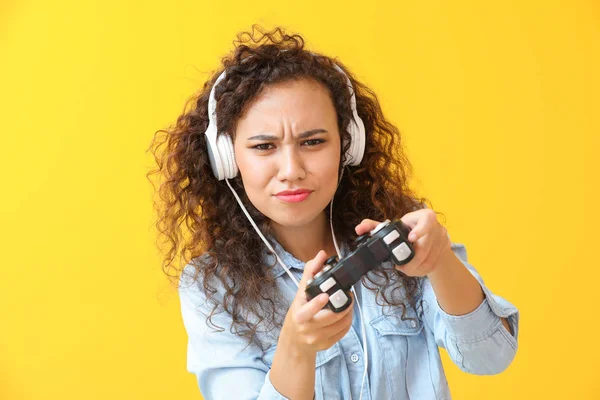African-American teenage girl playing video game on color background — Stock Photo, Image