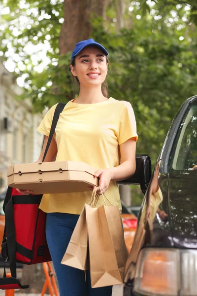 Female worker of food delivery service near car outdoors — Stock Photo, Image