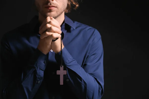 Религиозный молодой человек молится на тёмном фоне — стоковое фото