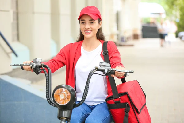Female worker of food delivery service riding scooter outdoors — Stock Photo, Image