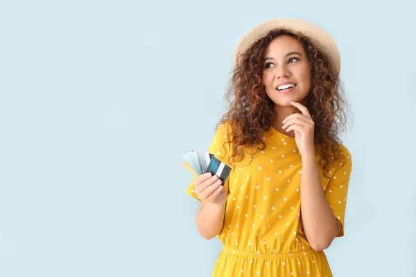 Thoughtful African-American woman with credit cards on light color background — Stock Photo, Image