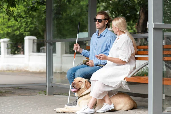 Blind young man with guide dog and mother waiting for bus outdoors — Stock Photo, Image