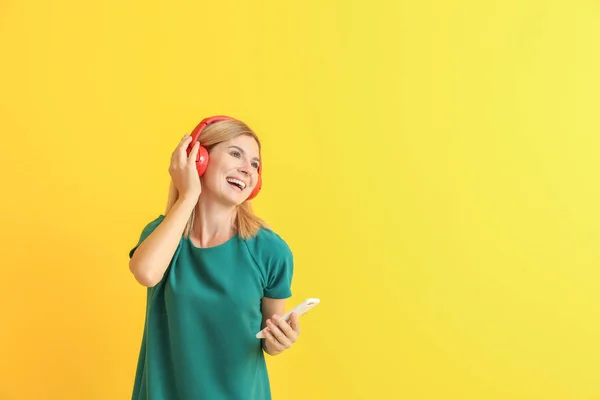 Happy beautiful woman listening to music on color background — Stock Photo, Image