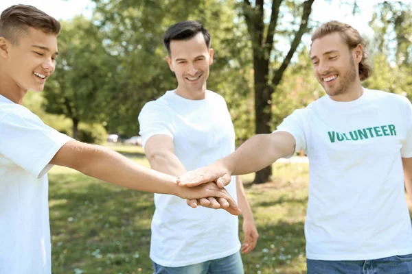 Equipo de voluntarios poniendo las manos juntas al aire libre — Foto de Stock