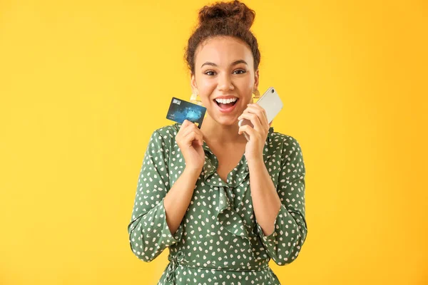 컬러 배경에 신용 카드와 휴대 전화와 행복한 아프리카 계 미국인 여성 — 스톡 사진