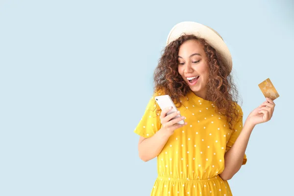 Счастливая афроамериканка с кредитной картой и мобильным телефоном на светлом фоне — стоковое фото