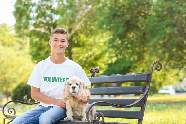 Teenage volunteer with cute dog sitting on bench outdoors — Stock Photo, Image