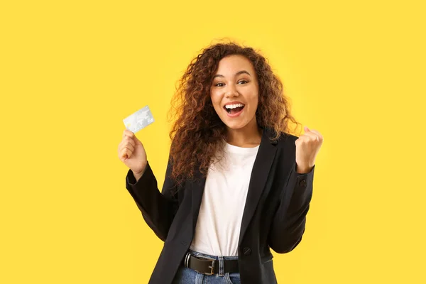 Happy African-American woman with credit card on color background — Stock Photo, Image