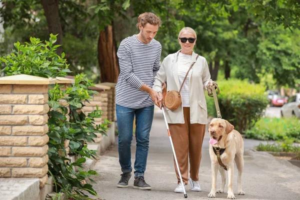 Blind mature woman with guide dog and son outdoors