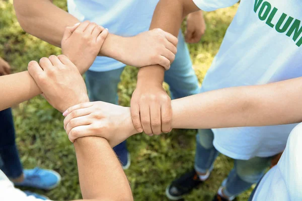 Team of volunteers holding hands together outdoors — Stock Photo, Image