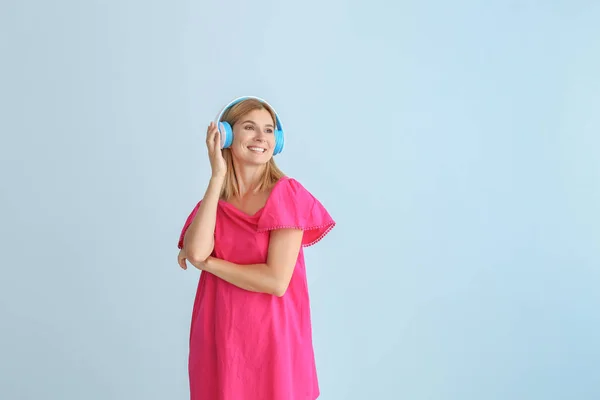 Gelukkig mooie vrouw luisteren naar muziek op kleur achtergrond — Stockfoto