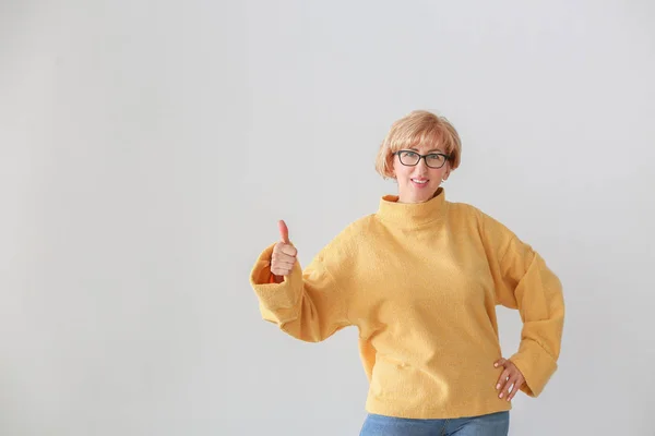 Портрет красивой женщины средних лет, показывающий большой палец вверх жест на светлом фоне — стоковое фото
