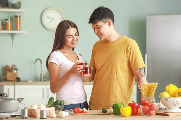 Boldog pár iszik lé főzés közben-ban konyha — Stock Fotó