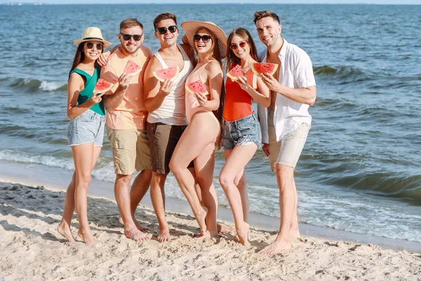 Happy friends eating watermelon on sea beach at resort — Stock Photo, Image