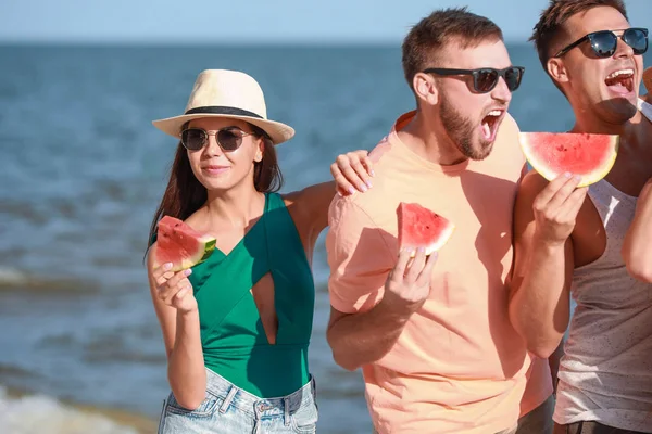 Heureux amis mangeant pastèque sur la plage de la mer à la station — Photo