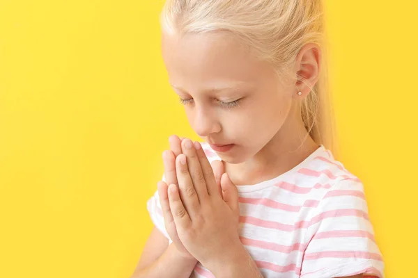 Little girl praying on color background — Stock Photo, Image