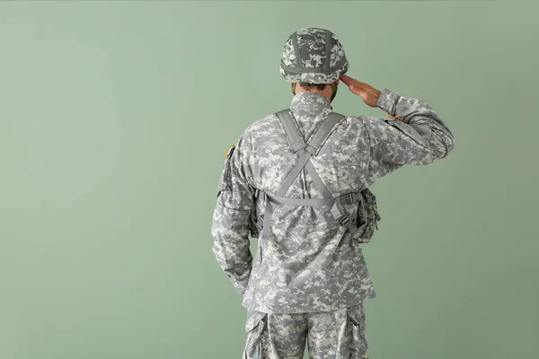 Saluting soldier on color background, back view — Stock Photo, Image