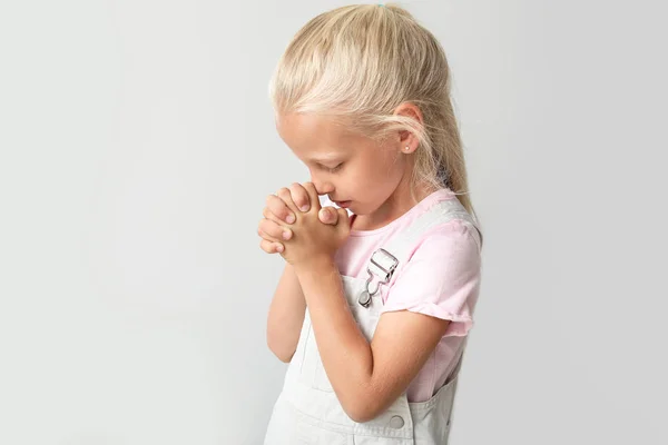 Μικρό κορίτσι προσεύχεται επάνω ελαφρύς υπόβαθρο — Φωτογραφία Αρχείου