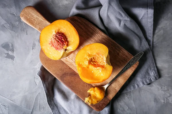 Wooden board with tasty peaches on grunge background — Stock Photo, Image