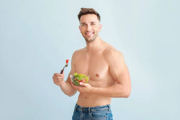 Handsome muscular man with salad on color background. Weight loss concept — Stock Photo, Image