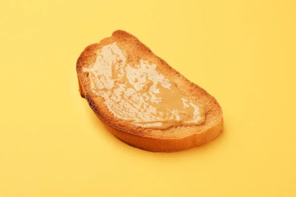 Tasty toasted bread with peanut butter on color background — Stock Photo, Image