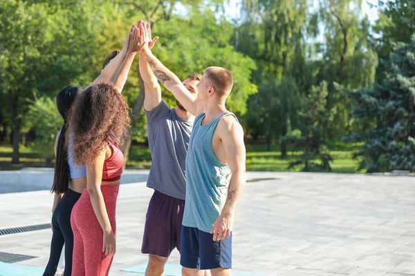 Grupo de jóvenes deportistas tomados de la mano al aire libre — Foto de Stock