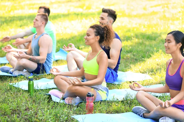 Група молодих спортсменів, які медитують разом на відкритому повітрі — стокове фото