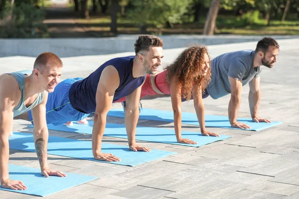 Grupo de jóvenes deportistas entrenando juntos al aire libre — Foto de Stock