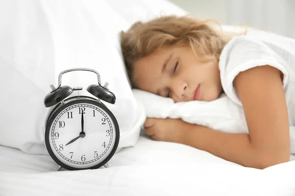 Sevimli uyuyan kızın yatağında çalar saat — Stok fotoğraf