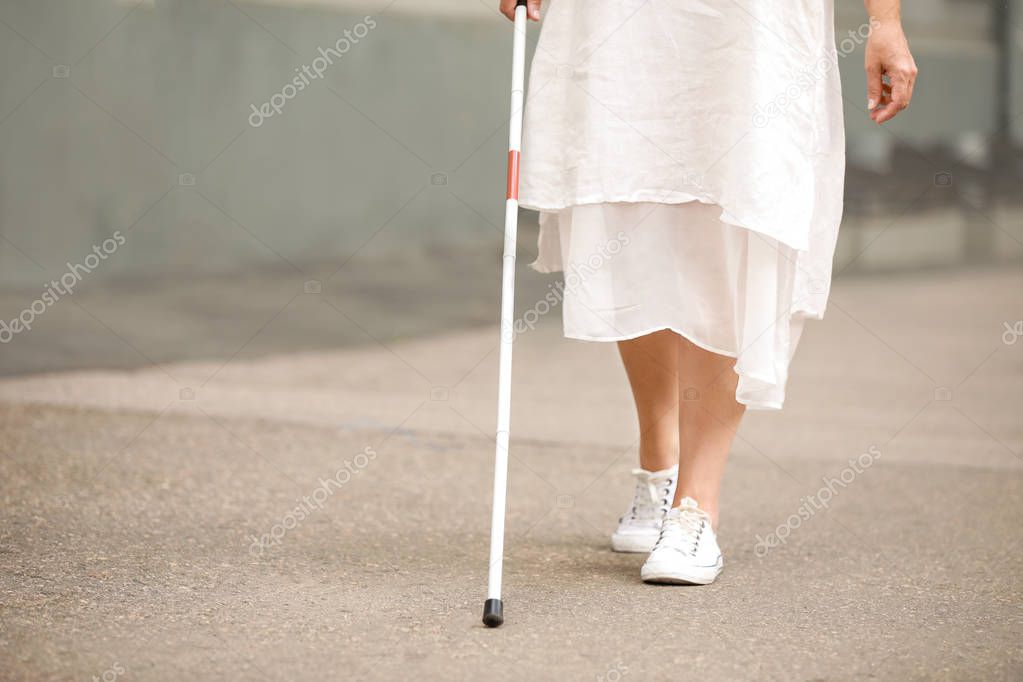 Blind mature woman walking outdoors
