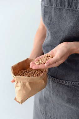 Kadın hafif arka plan üzerinde çiğ nohut ile çanta tutan, closeup