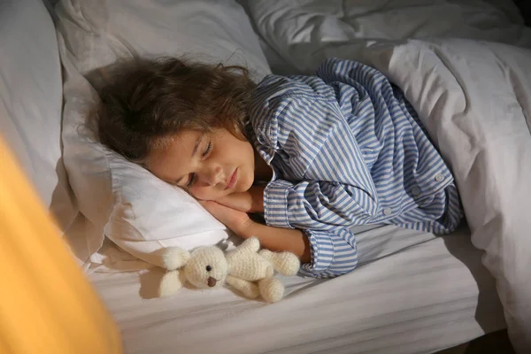 Χαριτωμένο κοριτσάκι κοιμάται στο κρεβάτι τη νύχτα — Φωτογραφία Αρχείου