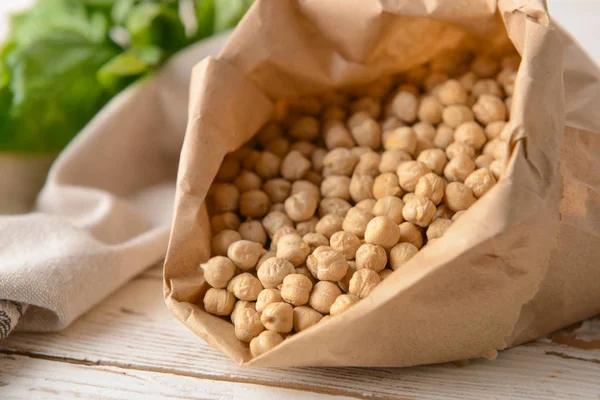Paper bag with raw chickpea on table, closeup