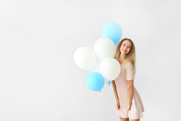 Красивая молодая женщина с воздушными шарами на светлом фоне — стоковое фото