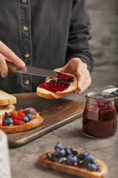 Woman spreading tasty berry jam onto toasted bread, closeup — Stock Photo, Image