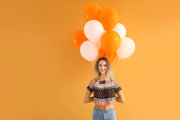 Beautiful young woman with balloons on color background — Stock Photo, Image