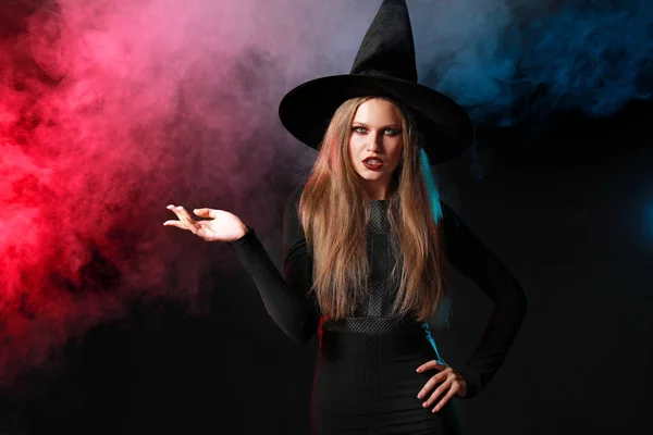 Красивая женщина, одетая как ведьма на Хэллоуин на темном фоне — стоковое фото