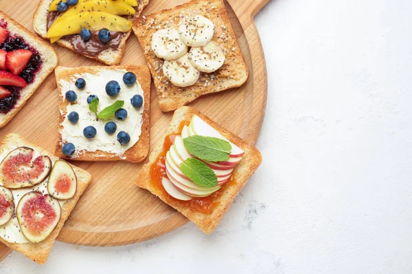 Board with tasty sandwiches on light background — Stock Photo, Image