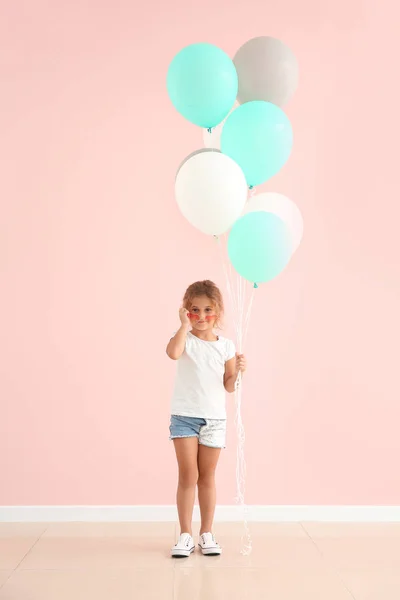 Kleines Mädchen mit Luftballons in der Nähe der Farbwand — Stockfoto
