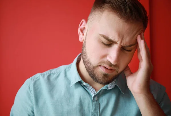 Young man suffering from headache on color background — Stock Photo, Image