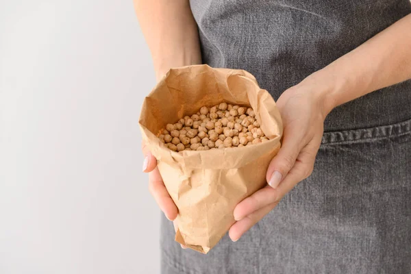 Kadın hafif arka plan üzerinde çiğ nohut ile çanta tutan, closeup
