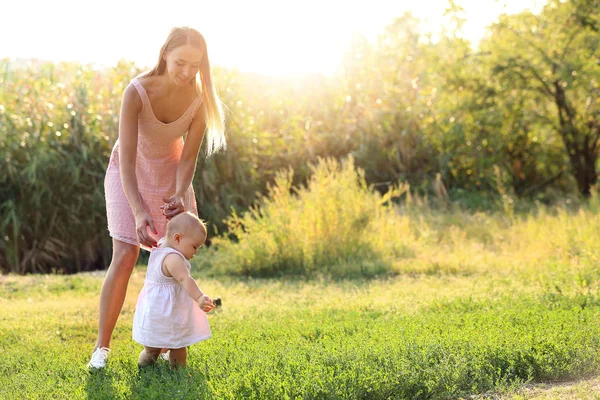 Mãe ensinando seu bebê a andar ao ar livre — Fotografia de Stock