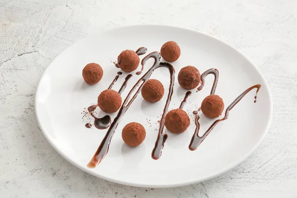 Läckra söta tryffel med chokladsås på tallrik — Stockfoto