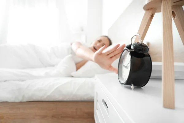 Morning of young woman turning off alarm clock while sleeping in bed — Stock Photo, Image